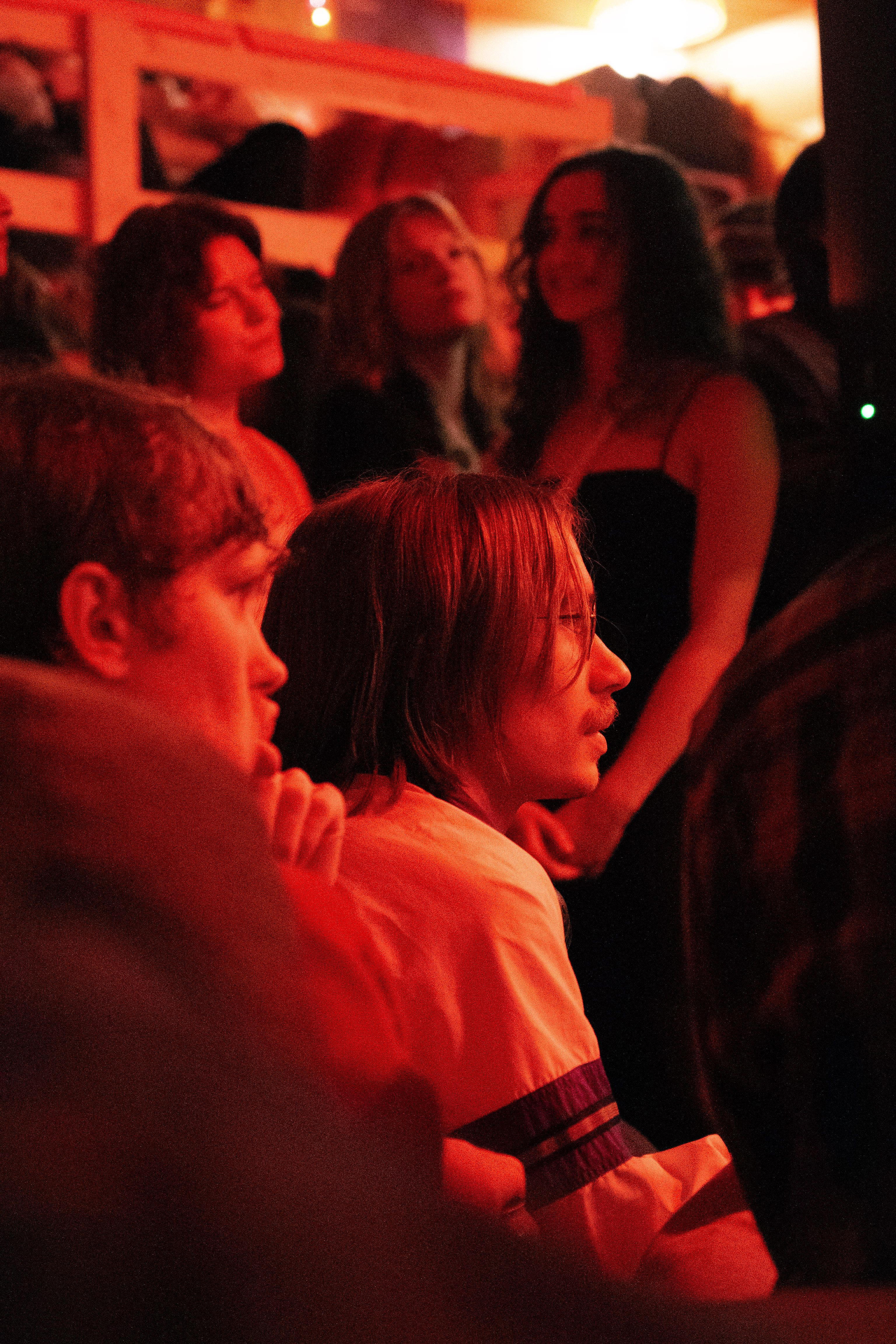Band playing in a warmly lit garage, with a crowd surrounding the stage.