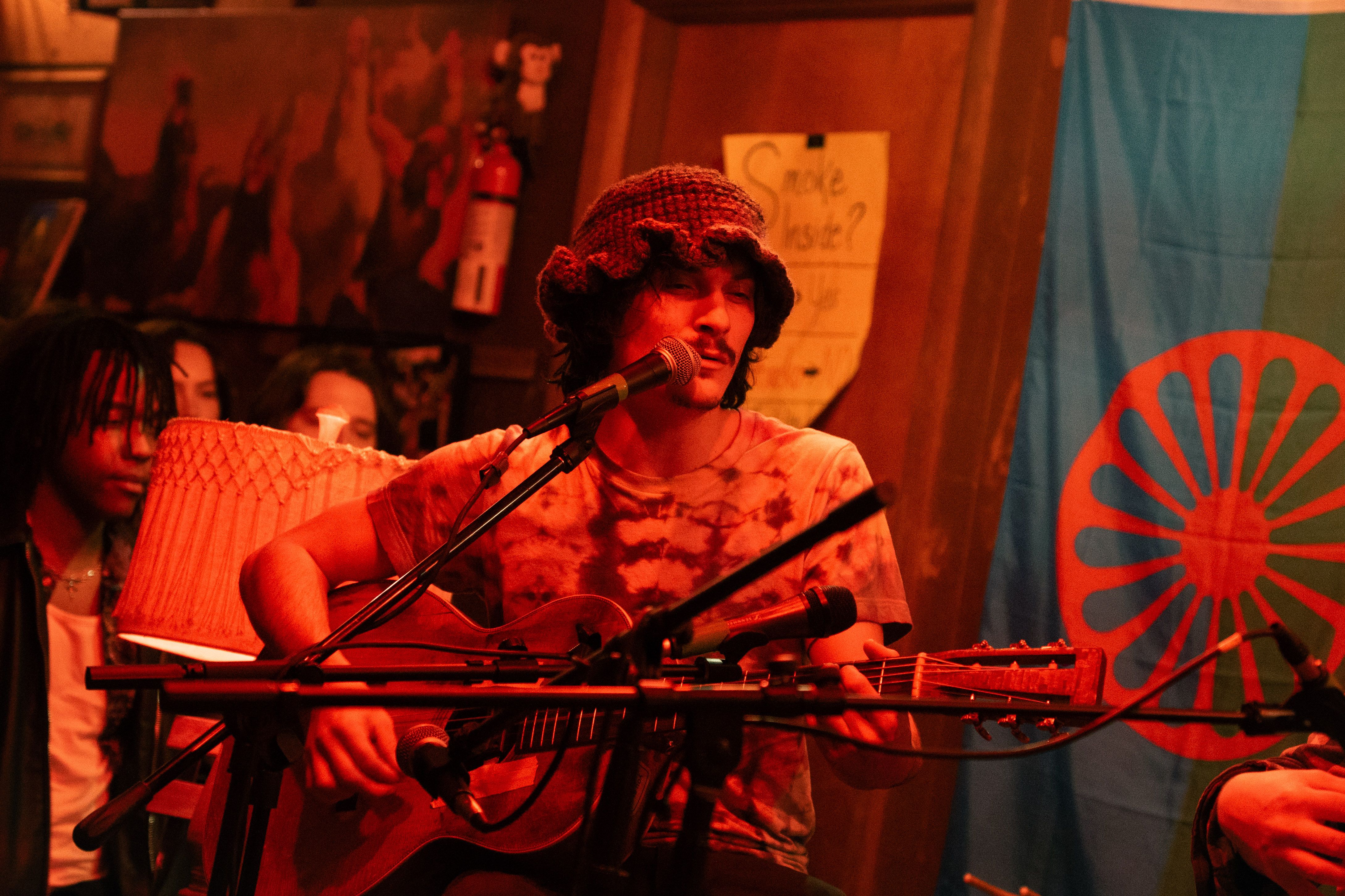 Band playing in a warmly lit garage, with a crowd surrounding the stage.