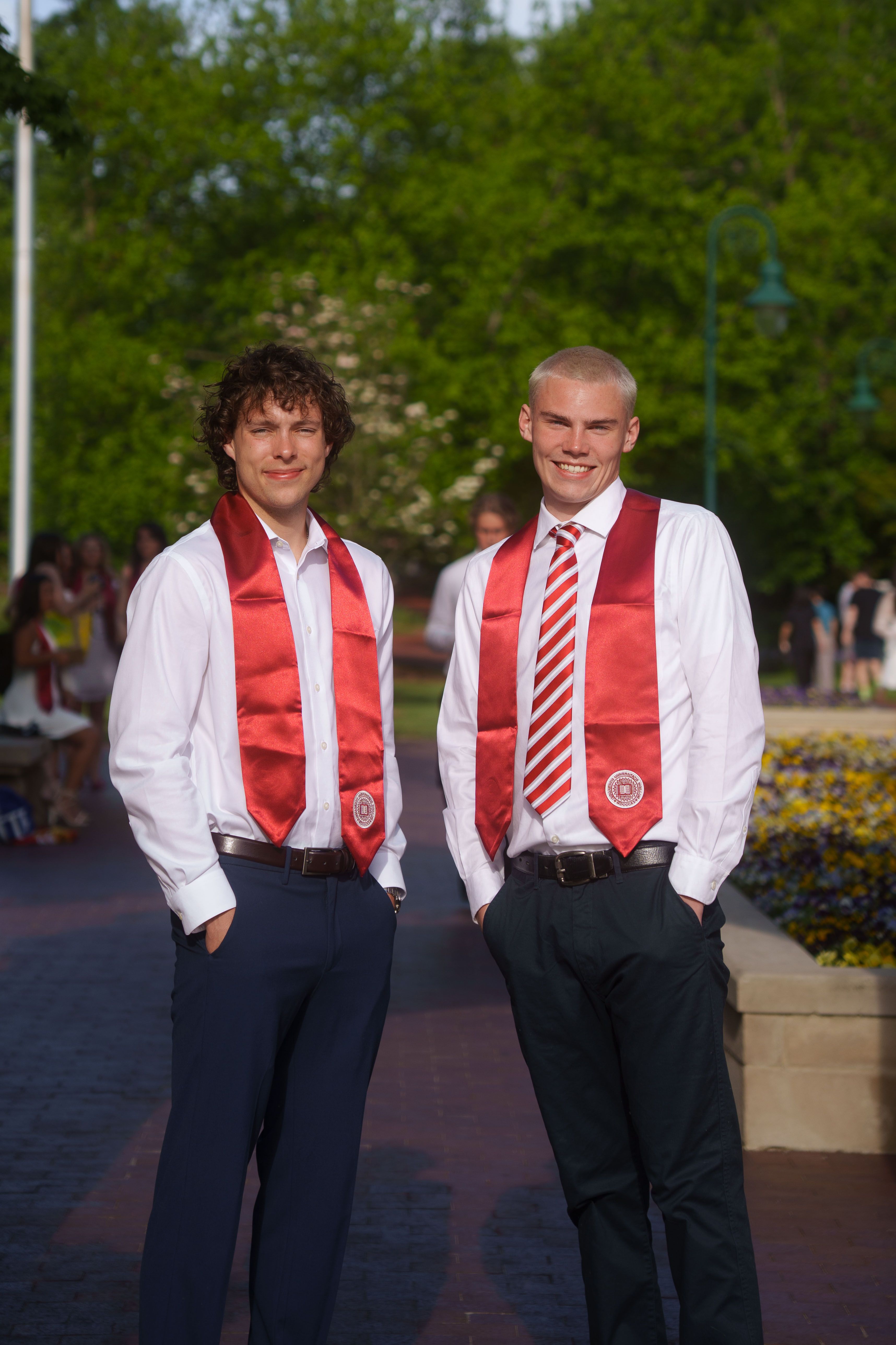 Three graduates in white dresses at sunset.