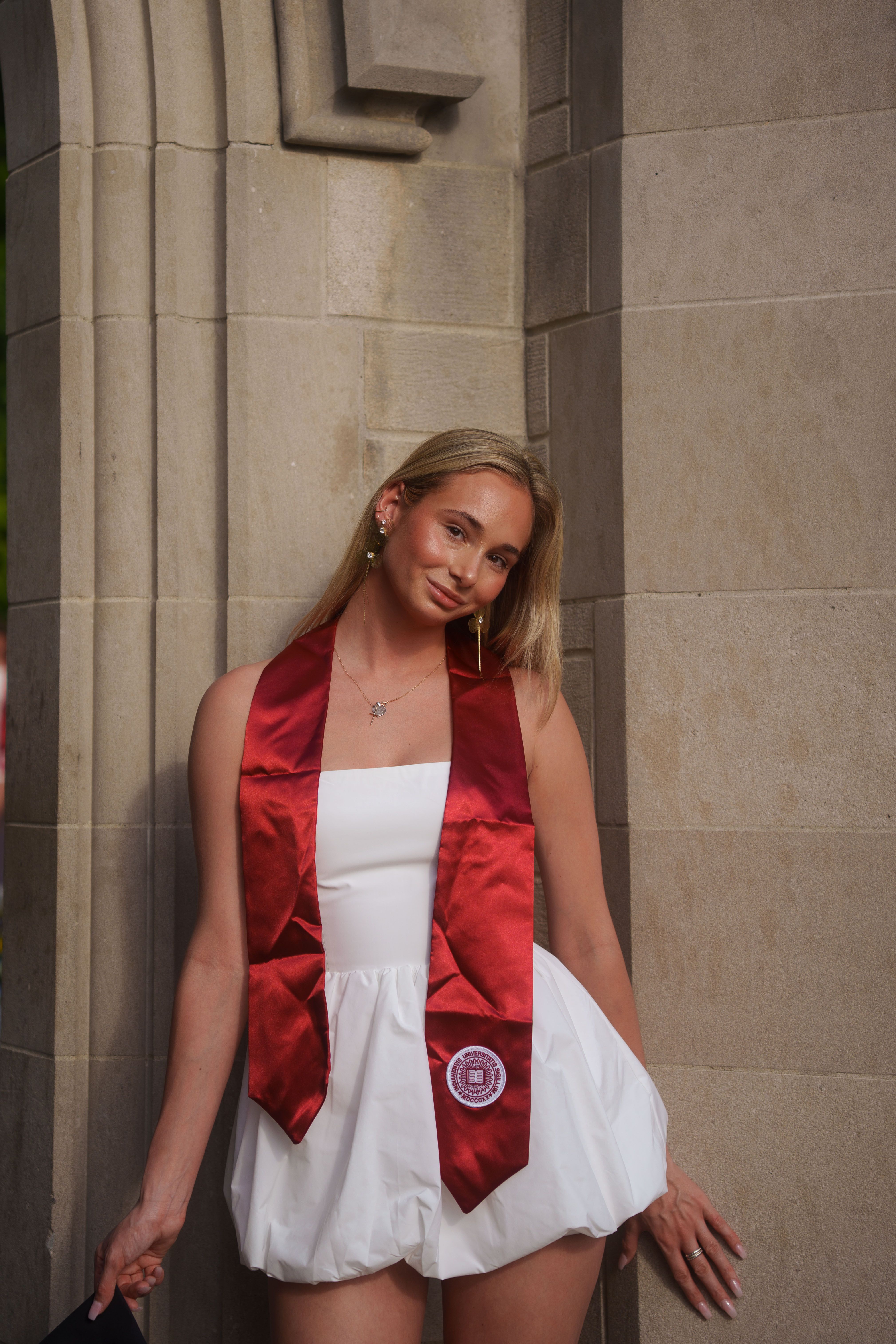 Three graduates in white dresses at sunset.