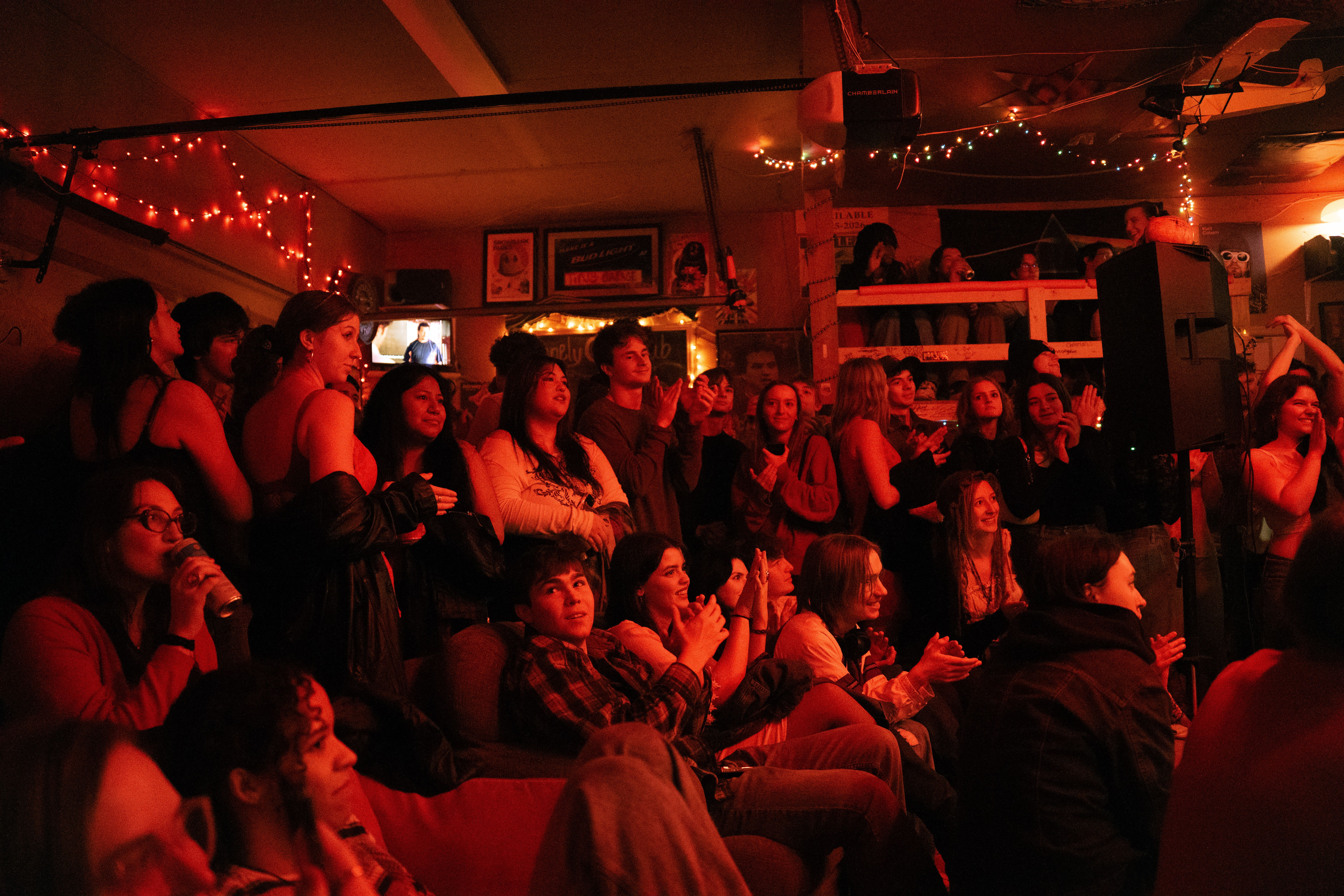 Band playing in a warmly lit garage, with a crowd surrounding the stage.