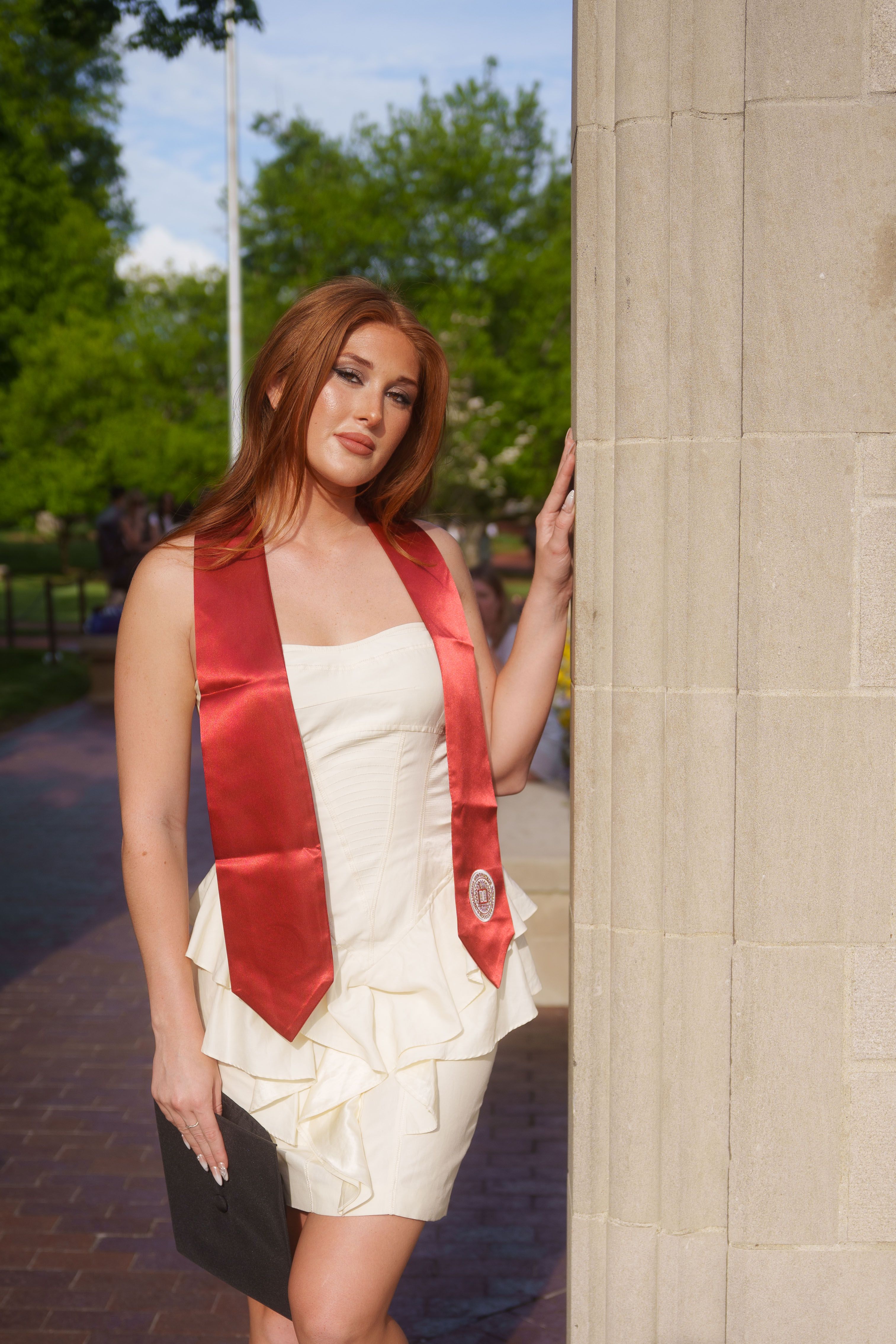 Three graduates in white dresses at sunset.
