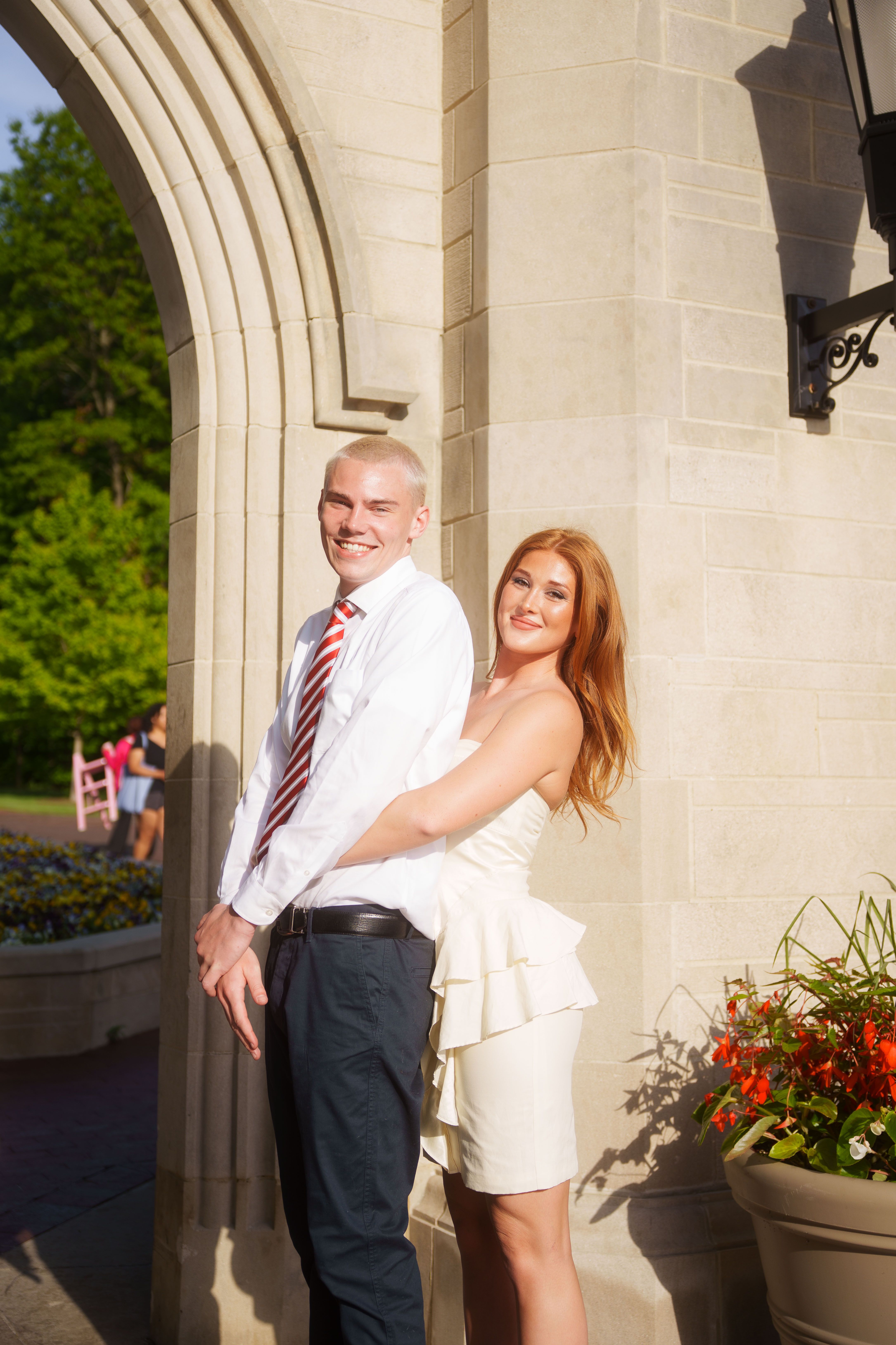Three graduates in white dresses at sunset.