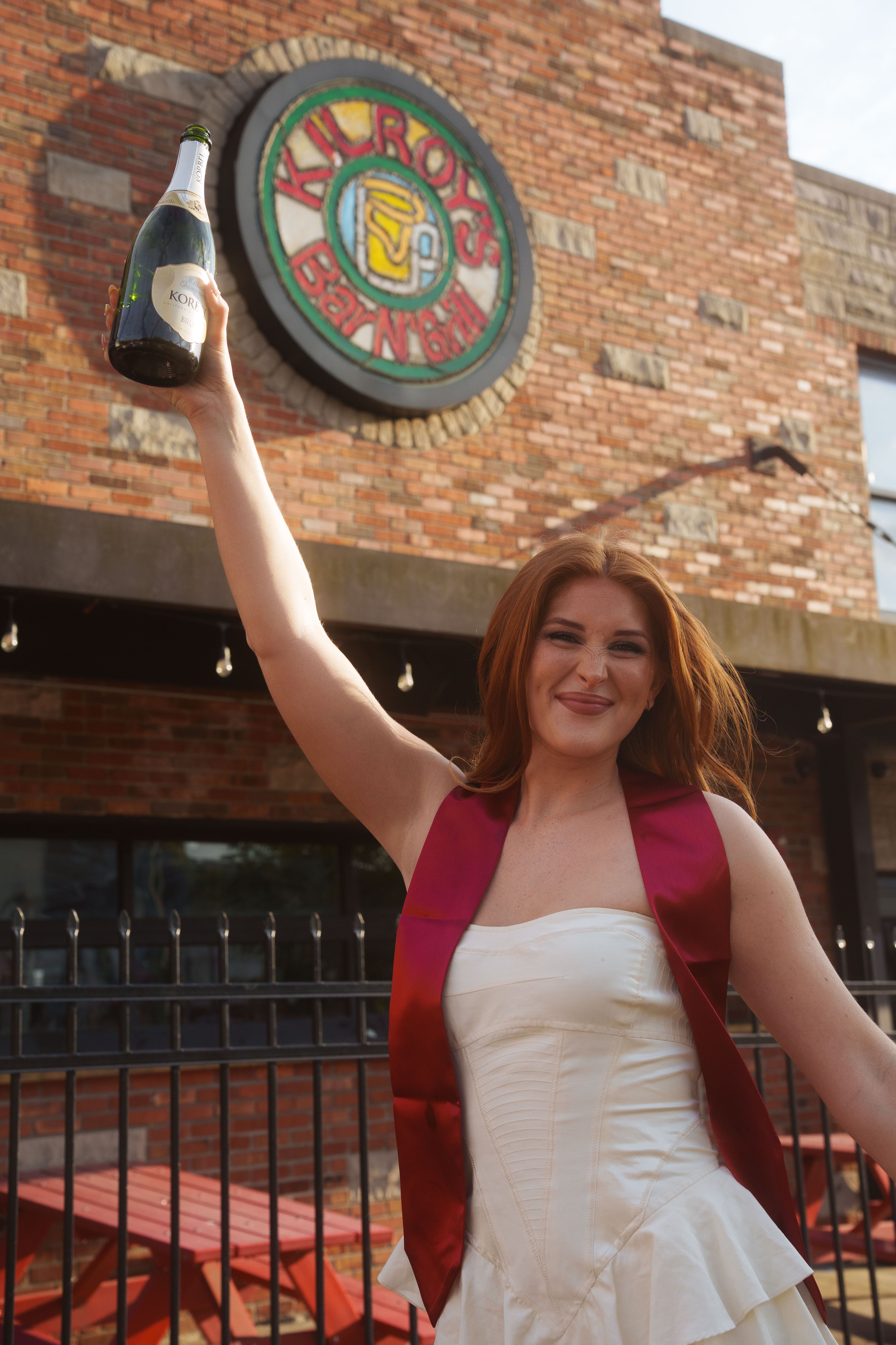 Three graduates in white dresses at sunset.