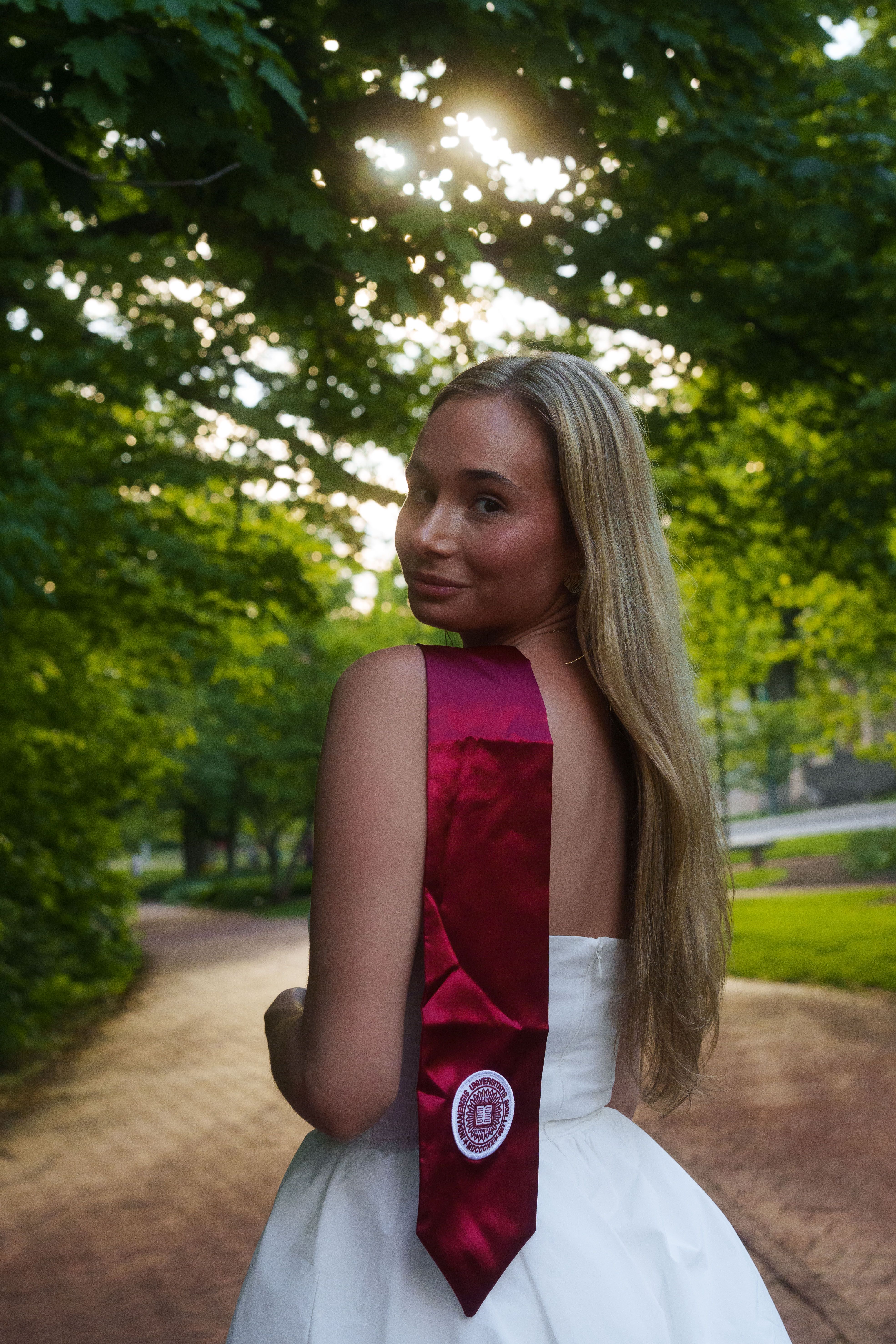 Three graduates in white dresses at sunset.