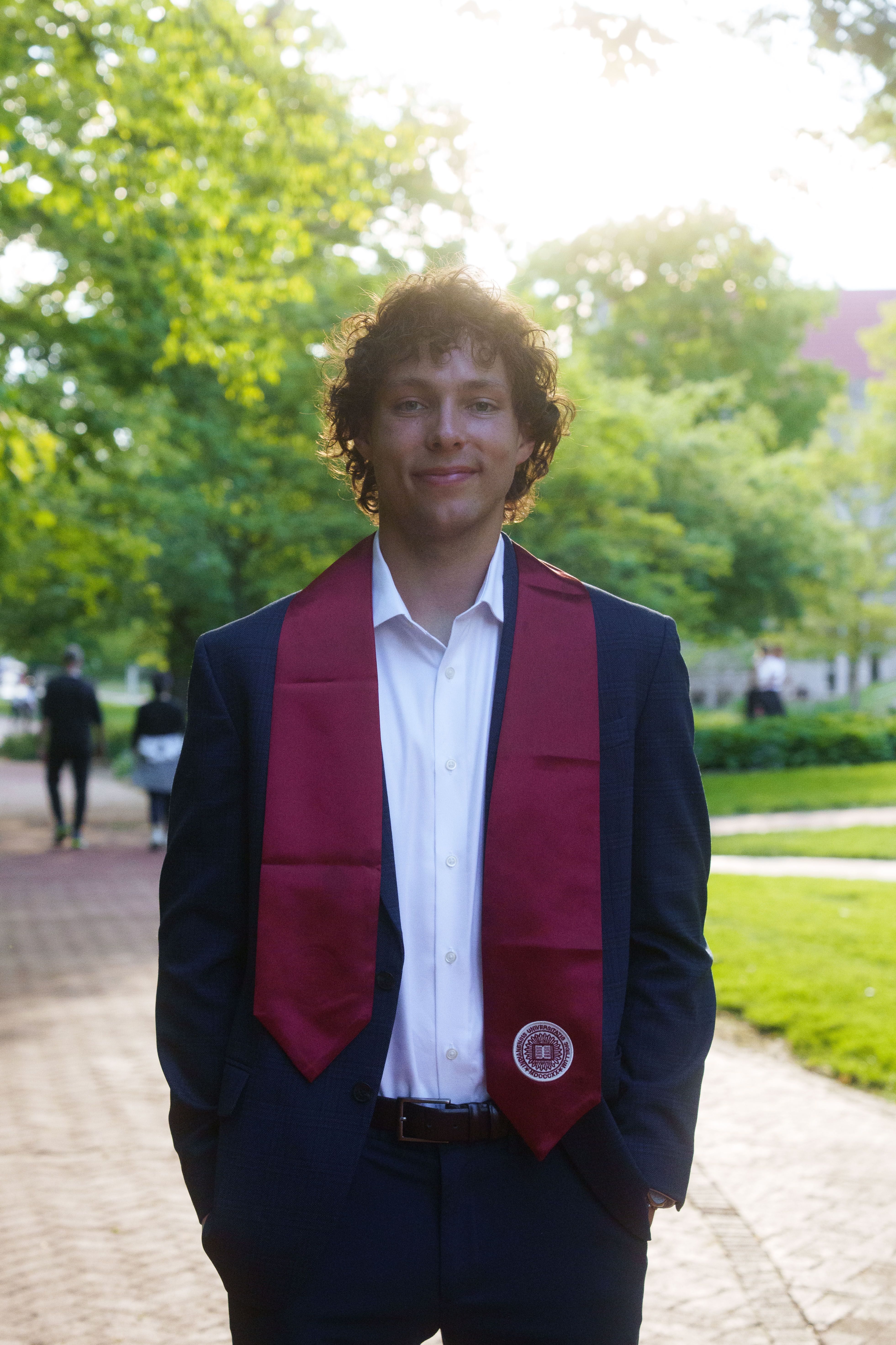 Three graduates in white dresses at sunset.