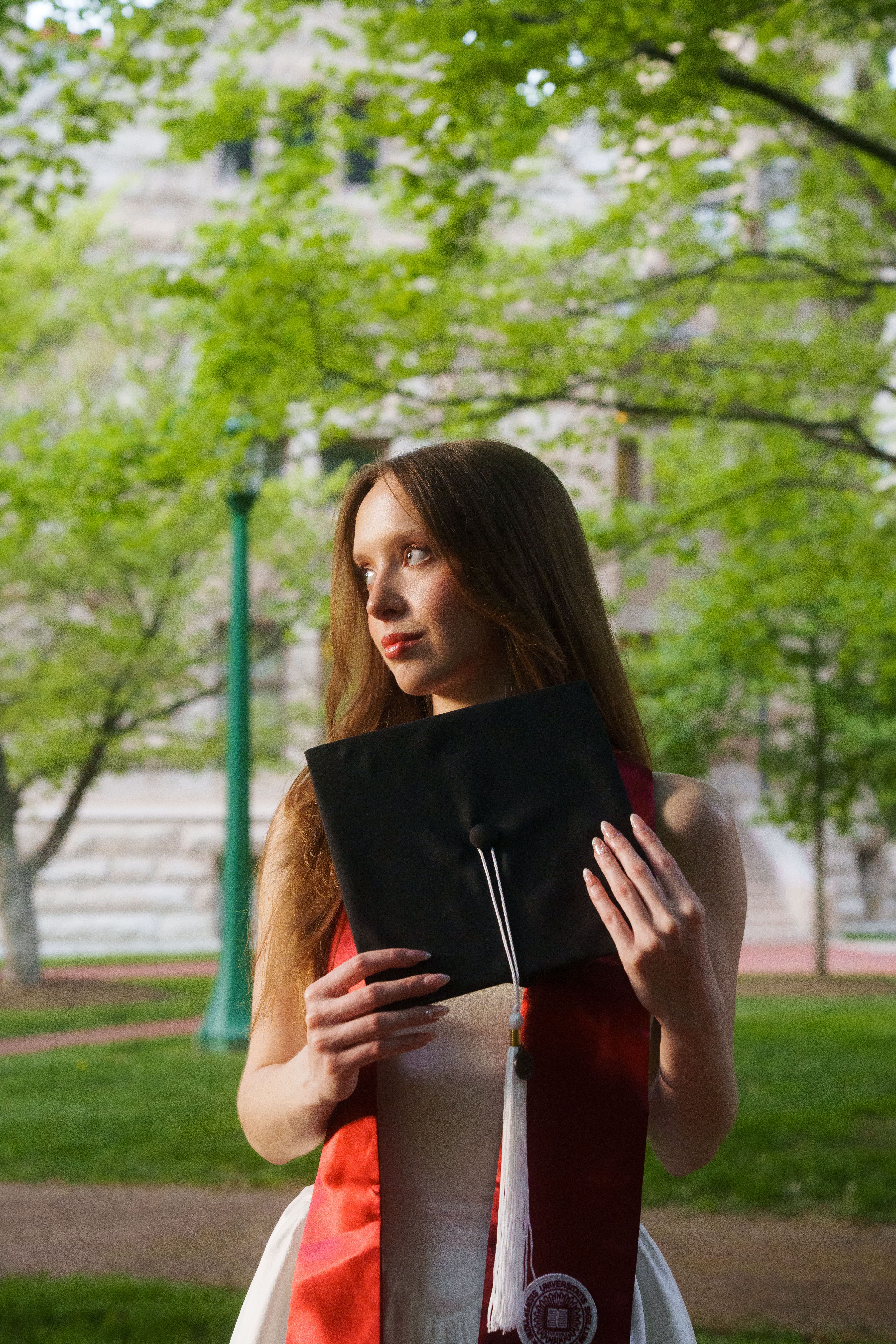 Three graduates in white dresses at sunset.