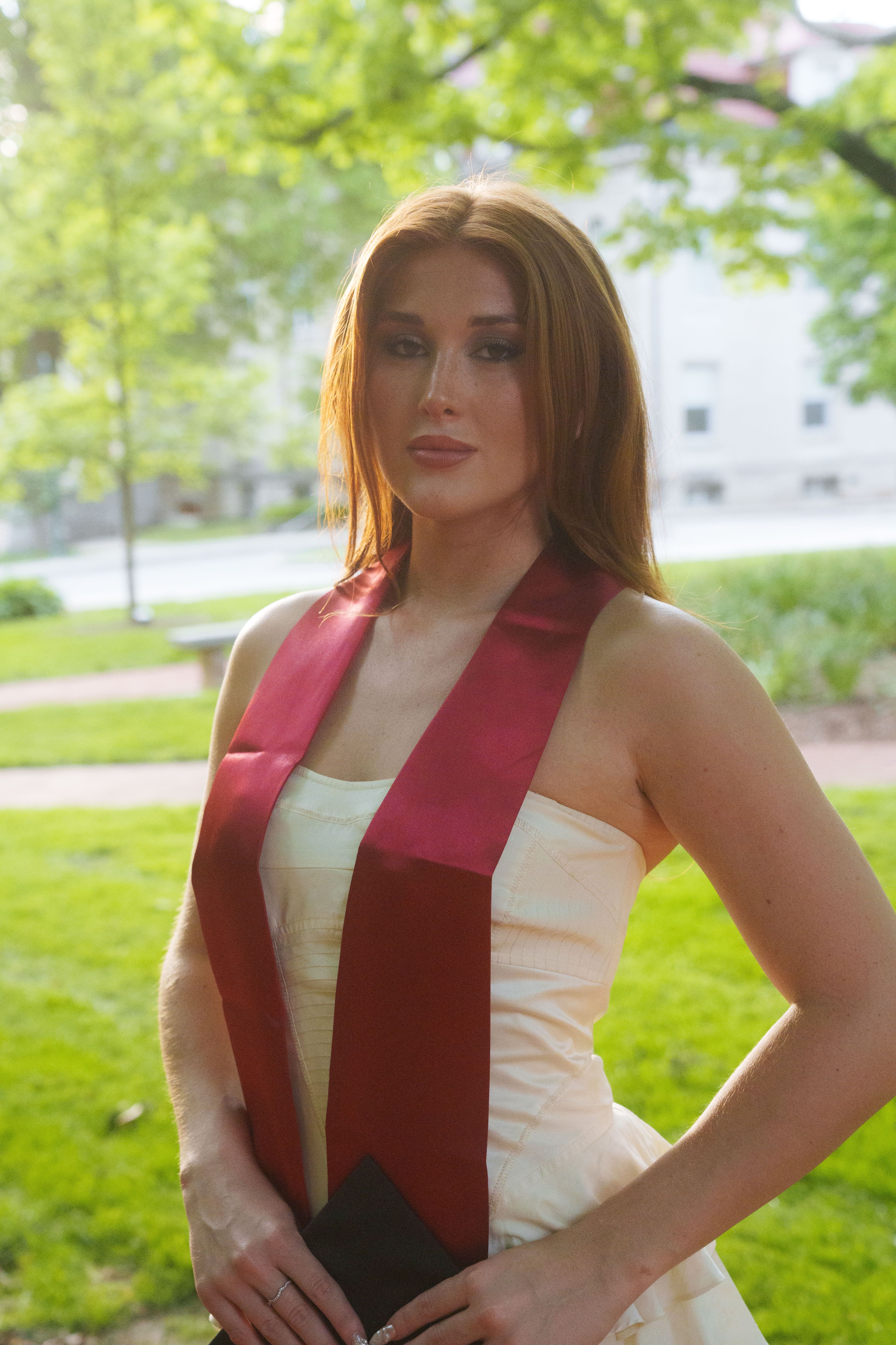 Three graduates in white dresses at sunset.
