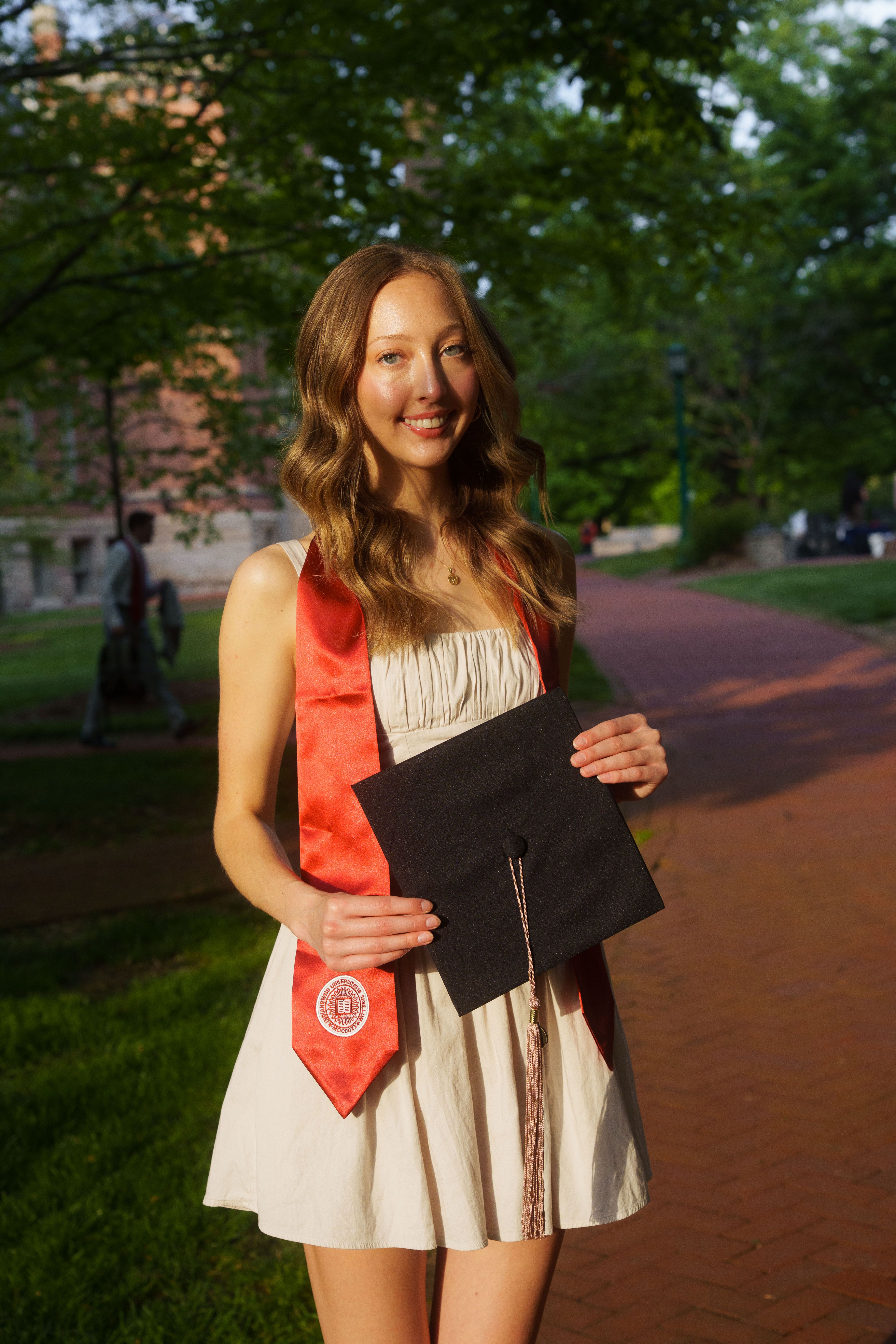 Three graduates in white dresses at sunset.