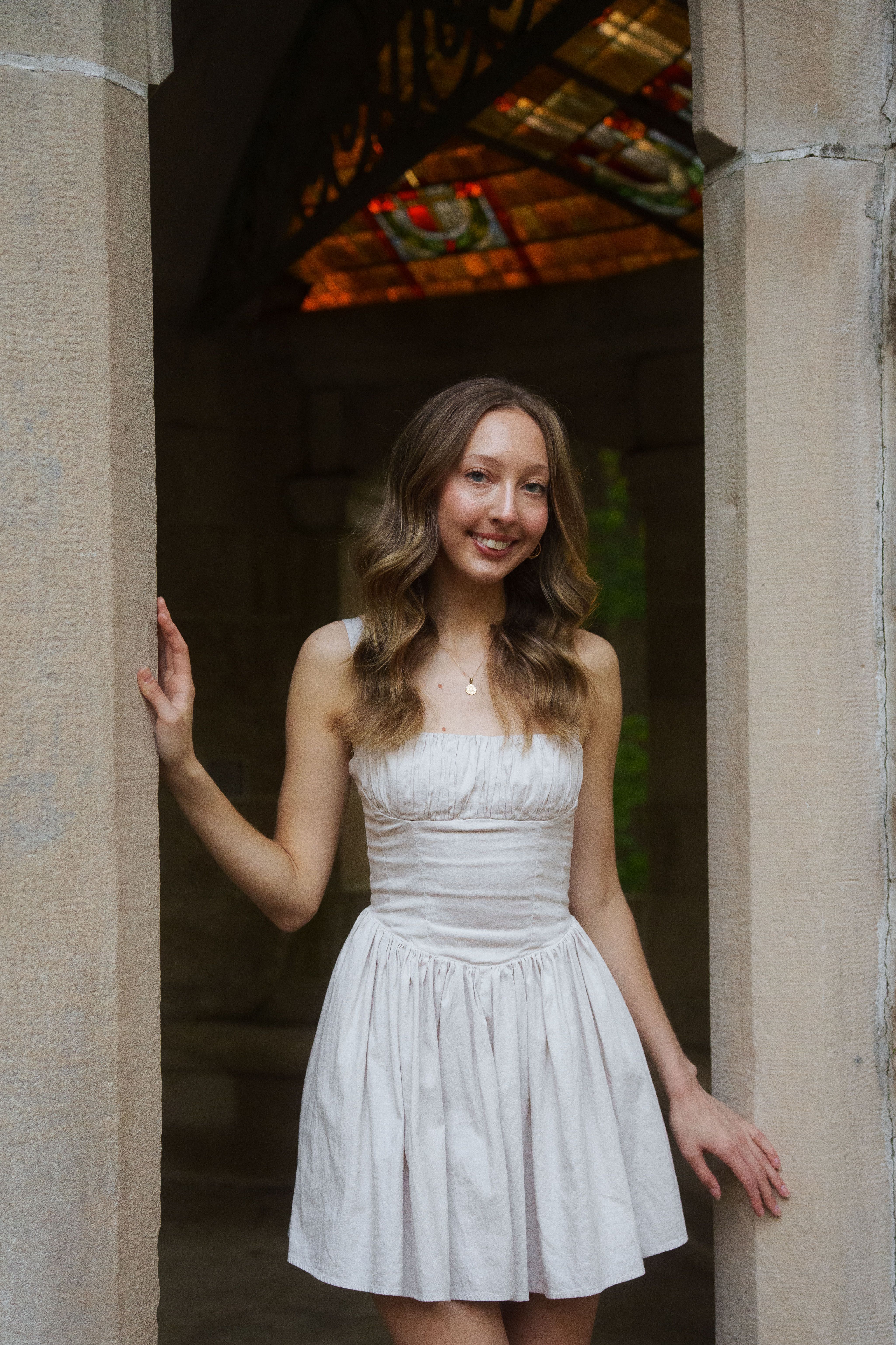 Three graduates in white dresses at sunset.