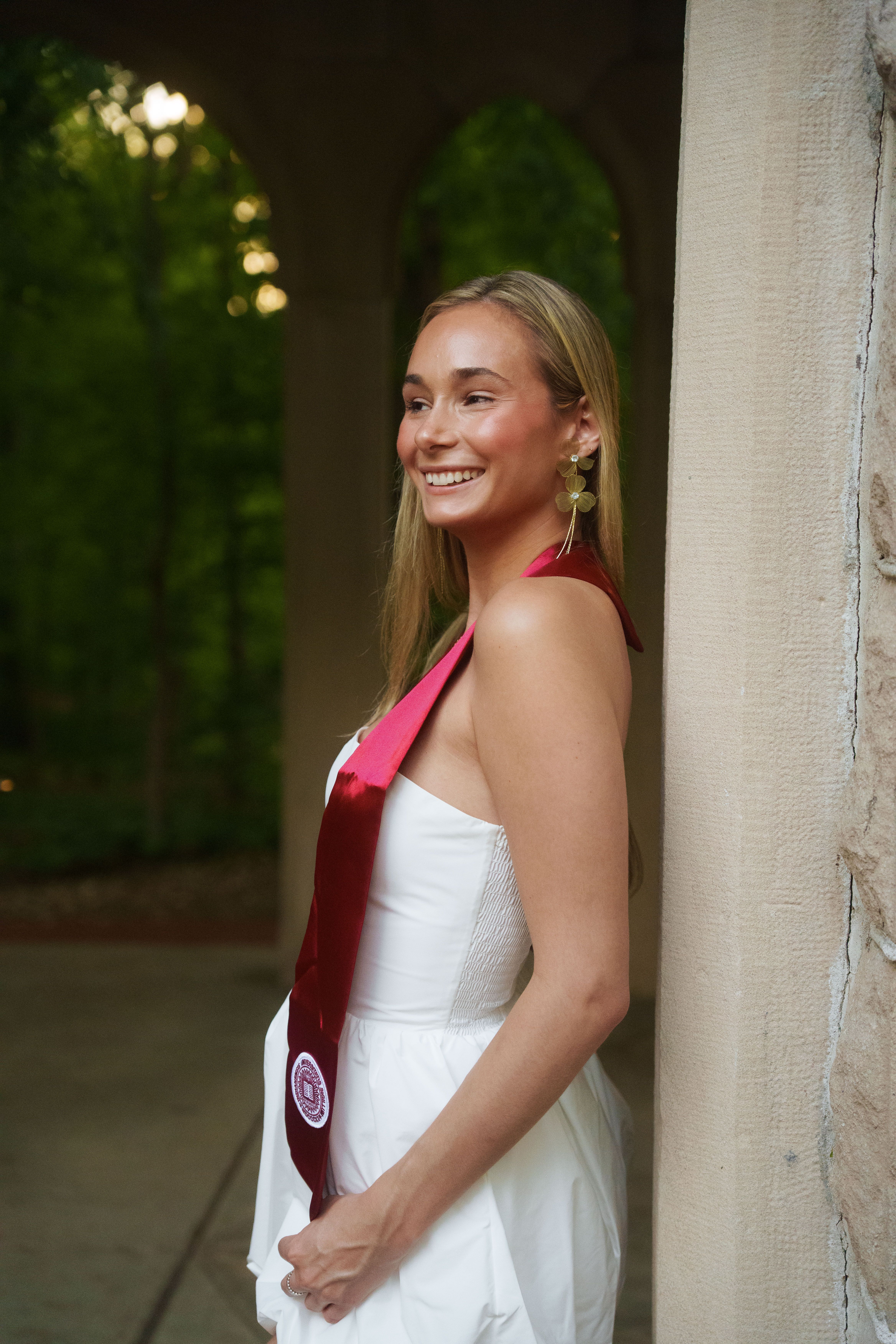 Three graduates in white dresses at sunset.