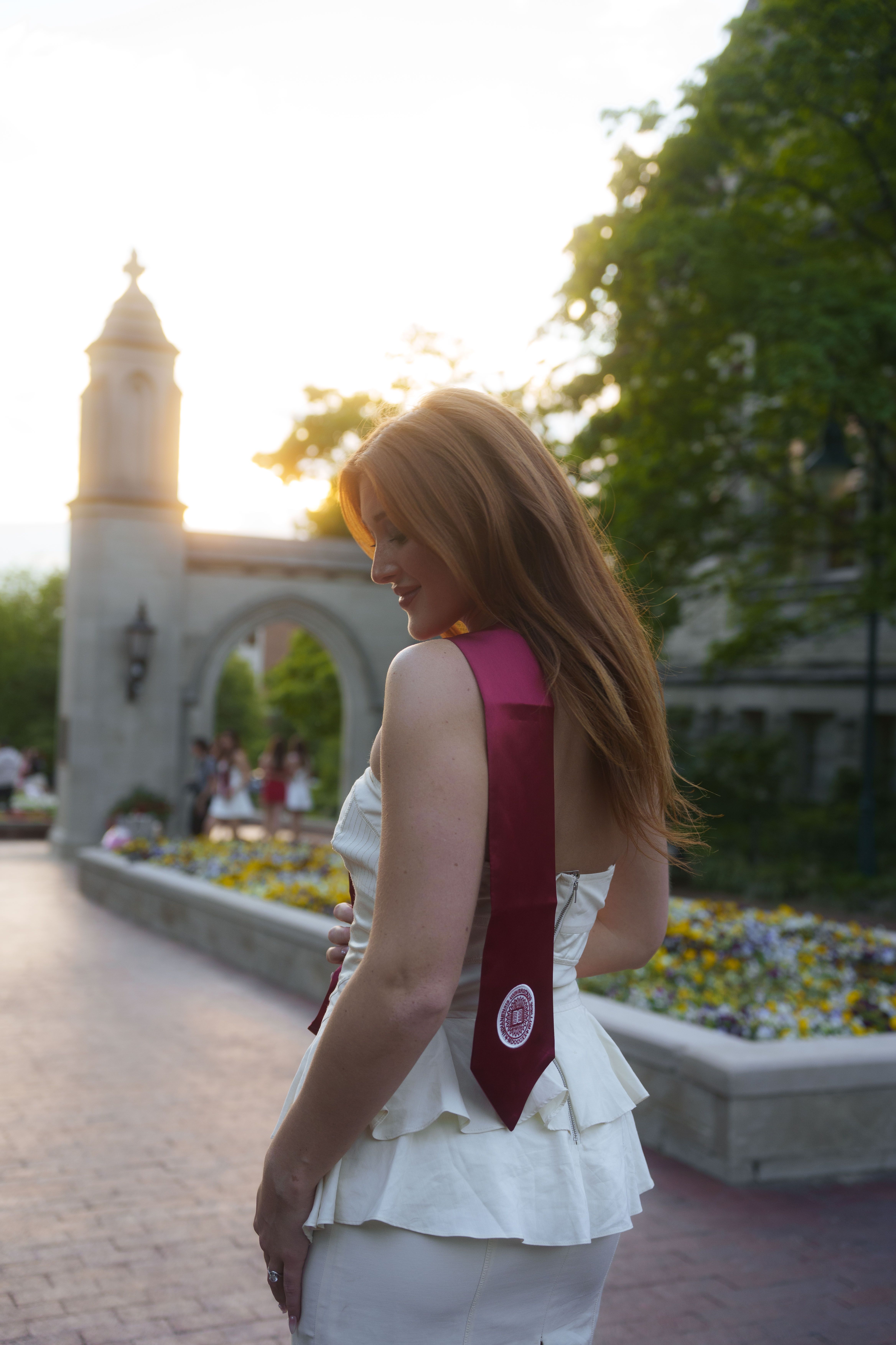 Three graduates in white dresses at sunset.